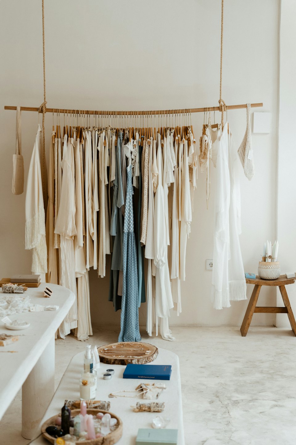 Boutique interior with wooden clothing rack and display tables.